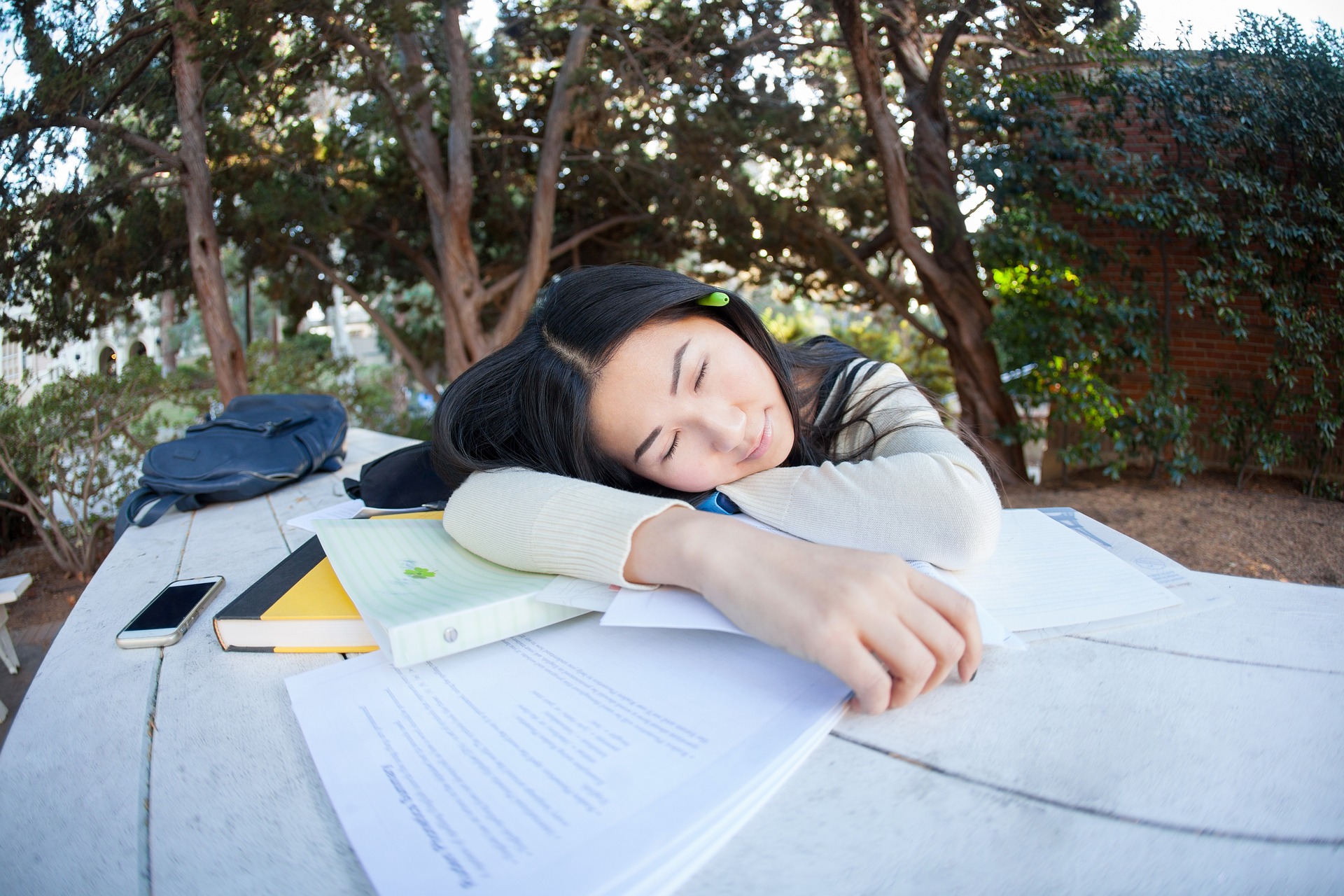 Väsynyt oppilas lepää pöydällä oppikirjojensa päällä.