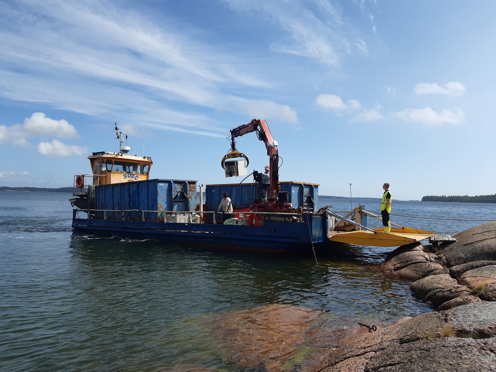 Jätteidenkeräyslautta ottaa roskia kyytiin saaristossa.